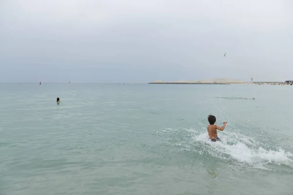 Çocuk denize spreyler ile çalışır.