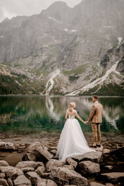 Polonya 'nın güneyindeki Tatra Dağları' ndaki Morskie Oko gölünde poz veren romantik gelin ve damat çifti.
