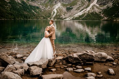 Polonya 'nın güneyindeki Tatra Dağları' ndaki Morskie Oko gölünde poz veren romantik gelin ve damat çifti.