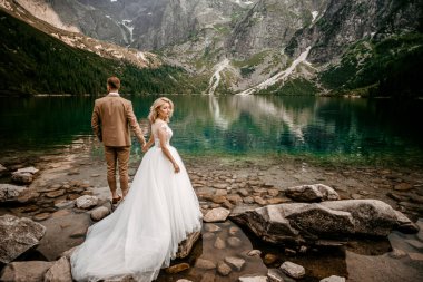 Polonya 'nın güneyindeki Tatra Dağları' nda Morskie Oko gölünde poz veren iki genç gelin ve damat.