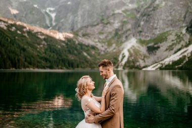 Polonya 'nın güneyindeki Tatra Dağları' nda Morskie Oko gölünde poz veren iki genç gelin ve damat.