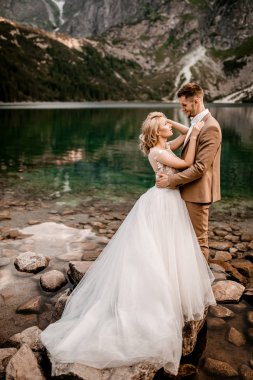 Polonya 'nın güneyindeki Tatra Dağları' nda Morskie Oko gölünde poz veren iki genç gelin ve damat.