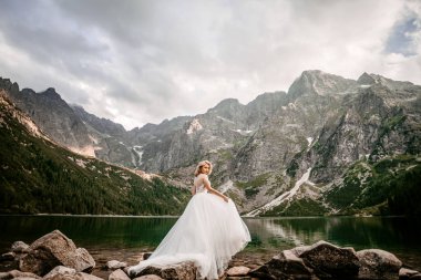Polonya 'nın güneyindeki Tatra Dağları' nda Morskie Oko gölünde poz veren uzun beyaz elbiseli güzel gelin.