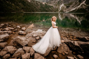 Polonya 'nın güneyindeki Tatra Dağları' nda Morskie Oko gölünde poz veren uzun beyaz elbiseli güzel gelin.