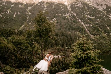 Polonya 'nın güneyindeki Tatra Dağları' nda Morskie Oko gölünde poz veren iki genç gelin ve damat.
