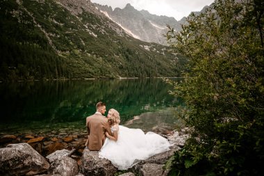Polonya 'nın güneyindeki Tatra Dağları' nda Morskie Oko Gölü 'nde poz veren harika genç bir çift gelin ve damat.