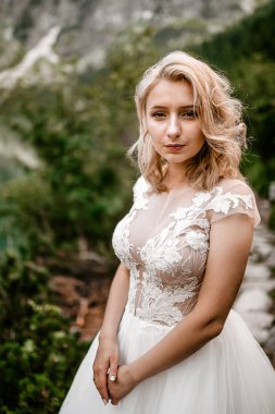 Polonya 'nın güneyindeki Tatra Dağları' nda Morskie Oko gölünde poz veren uzun beyaz elbiseli güzel gelin.