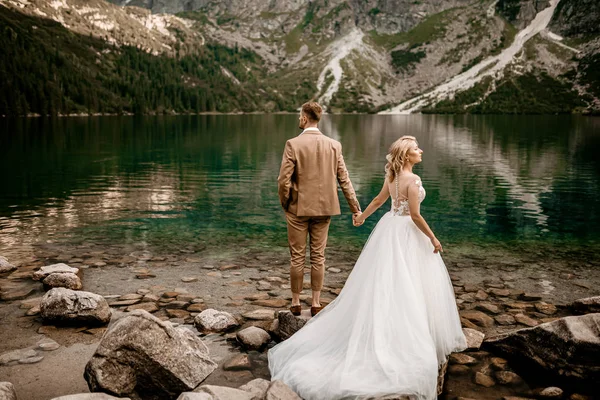 Genç gelin ve damat Polonya 'nın güneyindeki Tatra Dağları' nda Morskie Oko gölünde poz veriyorlar.