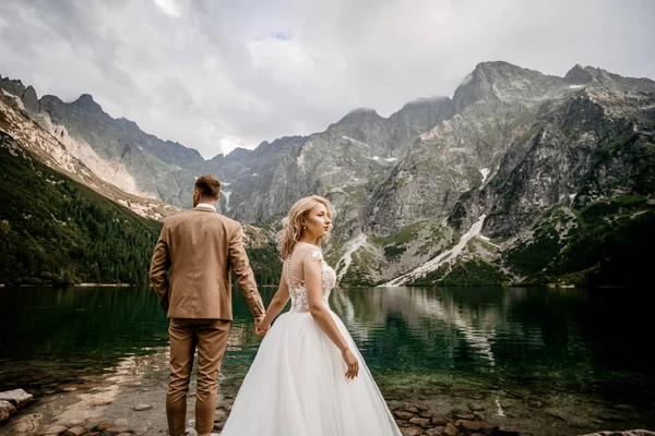 Genç gelin ve damat Polonya 'nın güneyindeki Tatra Dağları' nda Morskie Oko gölünde poz veriyorlar.
