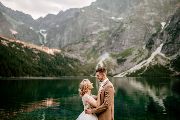 Couple of young bride and groom posing on lake Morskie Oko in the Tatra Mountains, in southern Poland