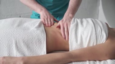 Anti-selülit masaj masörü bronzlaşmış genç bir kızın karnına masaj yapıyor.