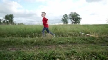 Küçük bir çocuk elinde bir uçurtmayla arazide koşuyor. Bir çocuk doğada yürümekten hoşlanır.