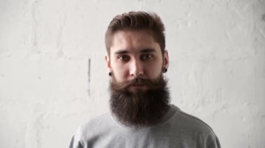 Güzel, güler yüzlü, kendine güvenen, sakallı adam. Yüzü kameraya bakıyor.