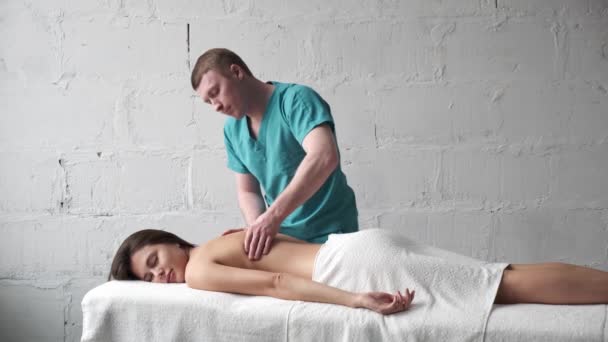 Junger Masseur tut Rückenmassage dunkles junges Mädchen. Massage Skoliose. Mädchen bekommt Vergnügen von einer entspannenden Rückenmassage — Stockvideo