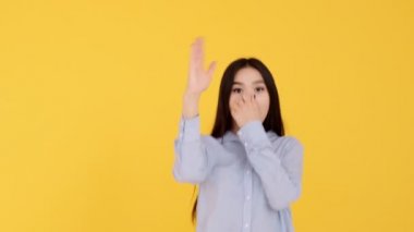 Sarı arka planda dans eden Asyalı kız. Yavaş çekim videosu. Kadın kamerayı kandırıyor