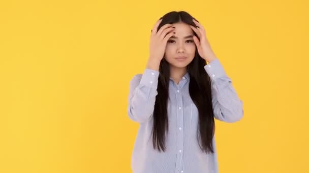 Jong Aziatisch meisje op gele achtergrond glimlachend en kijkend naar camera. blauw shirt — Stockvideo