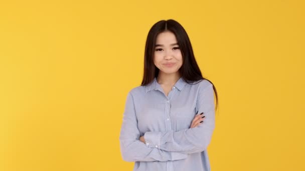 Joven chica asiática sobre fondo amarillo sonriendo y mirando a la cámara. camisa azul — Vídeos de Stock