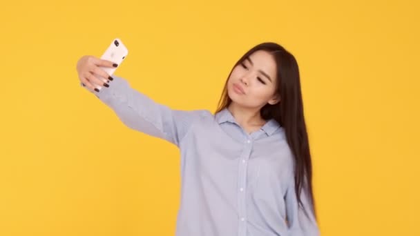 Ασιάτισσα σε κίτρινο φόντο κάνει μια selfie και στέλνει φωτογραφίες μέσω του Διαδικτύου — Αρχείο Βίντεο
