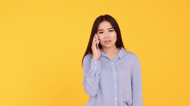 Aziatisch meisje op gele achtergrond praten over de telefoon. vrouw ruzies, scolds telefoon — Stockvideo