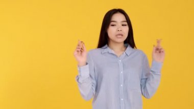Sarı arka plandaki Asyalı genç kız umutla dua ettim.