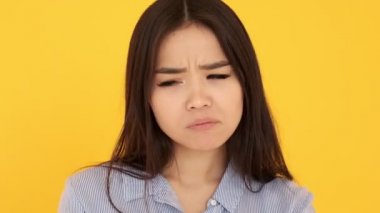 Sarı arka plandaki Asyalı kız memnuniyetsizliği gücendirdi. Ağlamak istiyor.