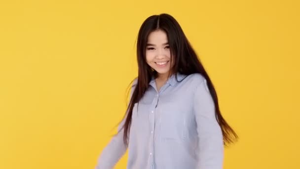 노란 배경의 여자가 카메라를 보며 활짝 웃고 있는 아시아 소녀 — 비디오