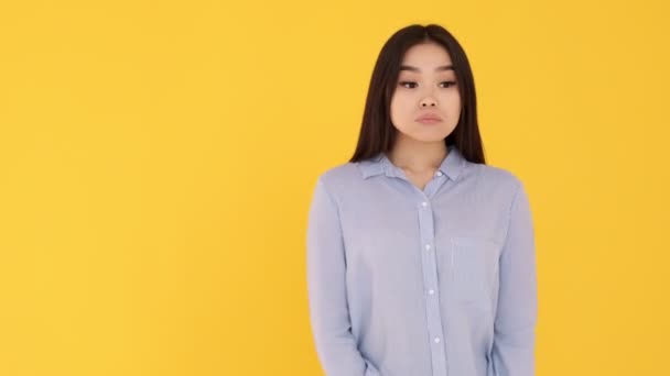 Triste niña infeliz pensando en un fondo amarillo. Mujer asiática pensando — Vídeos de Stock