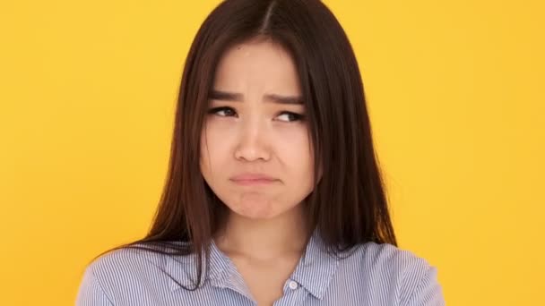 Ragazza asiatica su sfondo giallo primo piano offeso insoddisfatto. vuole piangere — Video Stock