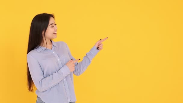 Chica sobre un fondo amarillo. muestra las manos en un espacio vacío. espacio de copia — Vídeos de Stock