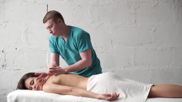 Jonge masseur doet terug Massage donker jong meisje. Masseer scoliose. Meisje krijgt plezier van een ontspannende rugmassage — Stockvideo