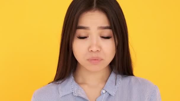 Девушка азиатка на жёлтом фоне крупным планом обиделась недовольна. хочет плакать — стоковое видео