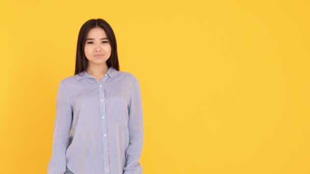 Девушка на жёлтом фоне. показывает руки на пустом месте. копировальное пространство — стоковое видео