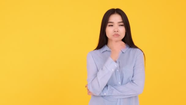 Chica asiática sobre un fondo amarillo. una persona reflexiva y una idea brillante — Vídeos de Stock