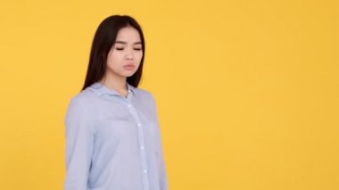 Sarı arka plandaki kız hayır diye bağırıyor. Asyalı kadın tatminsizliği reddediyor