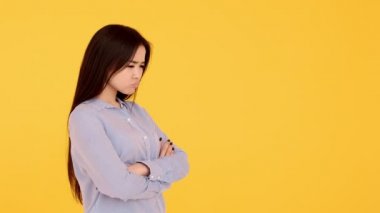Offended young girl Asian unhappy on a yellow background. copy space