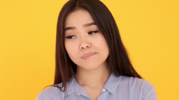 Fiatal lány elgondolkodva nézi kamera sárga háttér harapás ajka — Stock videók