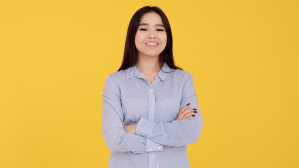Mladá asijská dívka ukazuje gesto OK na fotoaparátu na žlutém pozadí — Stock video