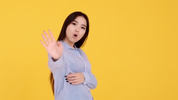 Girl on a yellow background screams no. woman Asian girl denies dissatisfaction — Stock Video