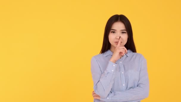 Девушка на желтом фоне показывает жест молчания — стоковое видео