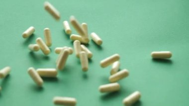 Yavaş çekim hapları yeşil arka plana düşüyor. İlaç takviyeleri yakın plan.