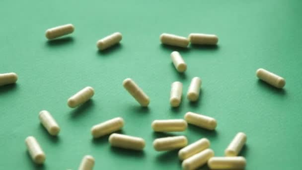 Píldoras de vídeo de cámara lenta cayendo sobre fondo verde. pastillas suplementos primer plano — Vídeos de Stock