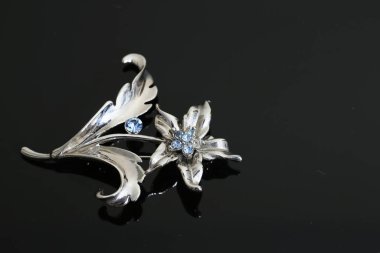 Gümüş çiçekli ve mücevherli bir broş.