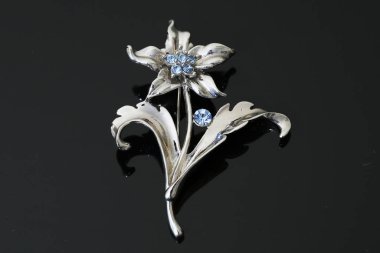 Gümüş çiçekli ve mücevherli bir broş.