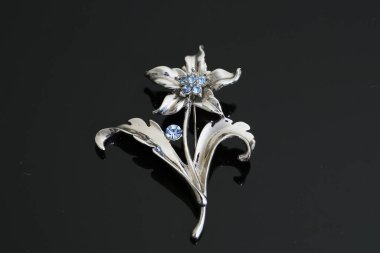 Gümüş çiçekli ve mücevherli bir broş.