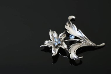 Gümüş çiçekli ve mücevherli bir broş.