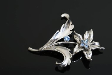 Gümüş çiçekli ve mücevherli bir broş.
