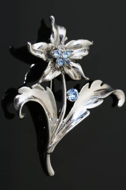 Gümüş çiçekli ve mücevherli bir broş.