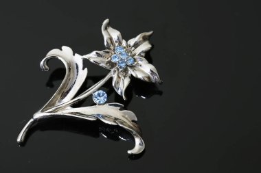 Gümüş çiçekli ve mücevherli bir broş.