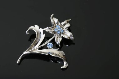 Gümüş çiçekli ve mücevherli bir broş.