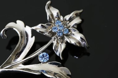 Gümüş çiçekli ve mücevherli bir broş.